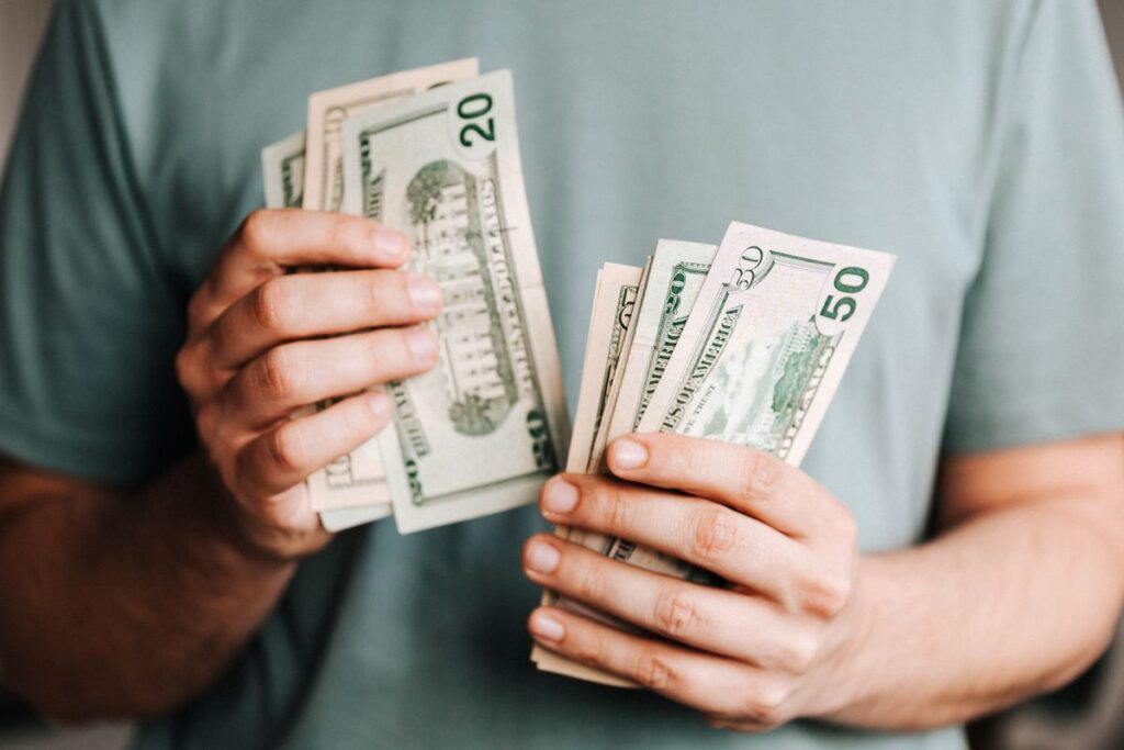 Manos contando billetes representando ahorro en hosting con Hostinger