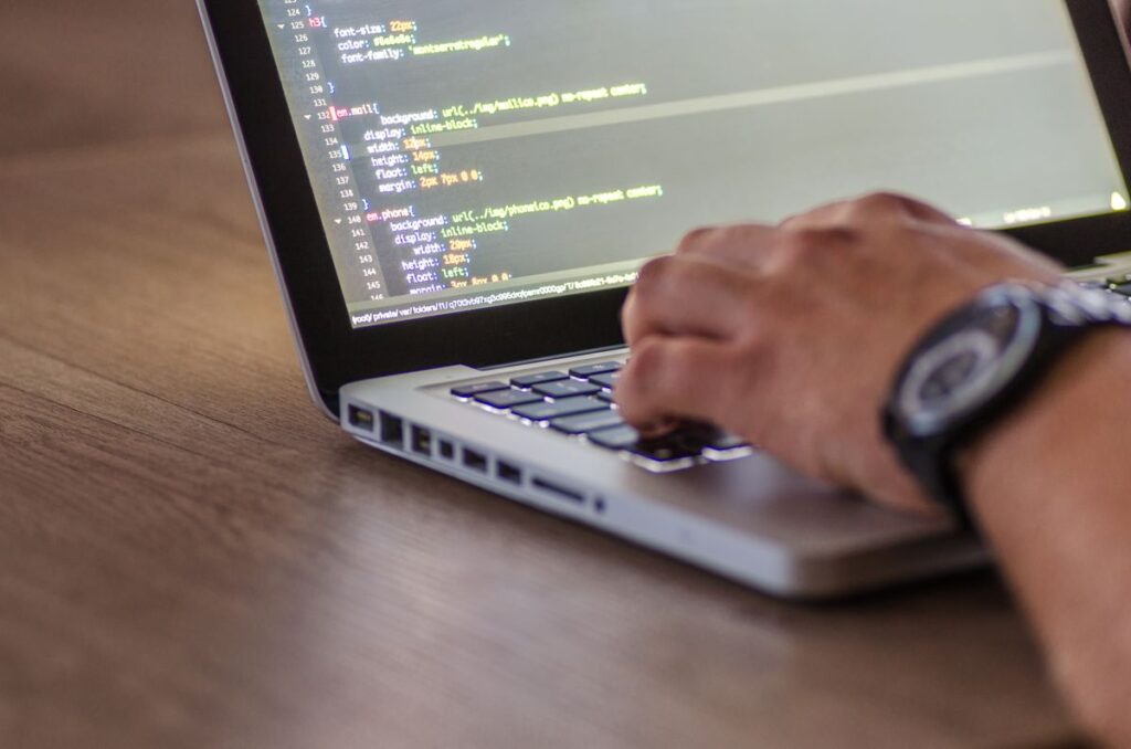 Manos escribiendo código CSS en laptop durante la configuración de WordPress